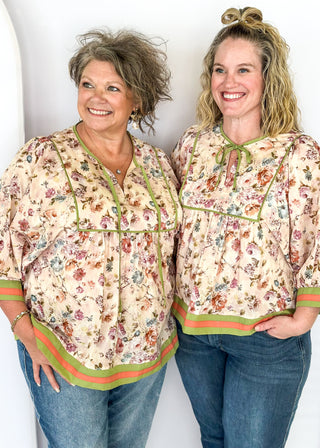 Soft floral Babydoll top with 3/4 puff sleeve, orange and green strip detail on banding of hem and sleeve. green ribbon detail on the front and tie at the collar.
