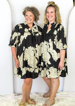 Black knee length dress with large white florals. 3/4 length flowy sleeve. Black scallop detail on chest. Lined
