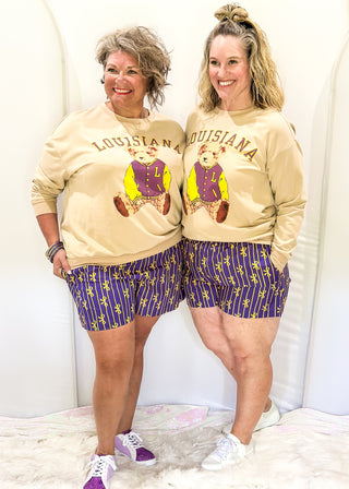Purple boxer shorts with pockets. Gold stripe pattern with bows throughout. Elastic waist.