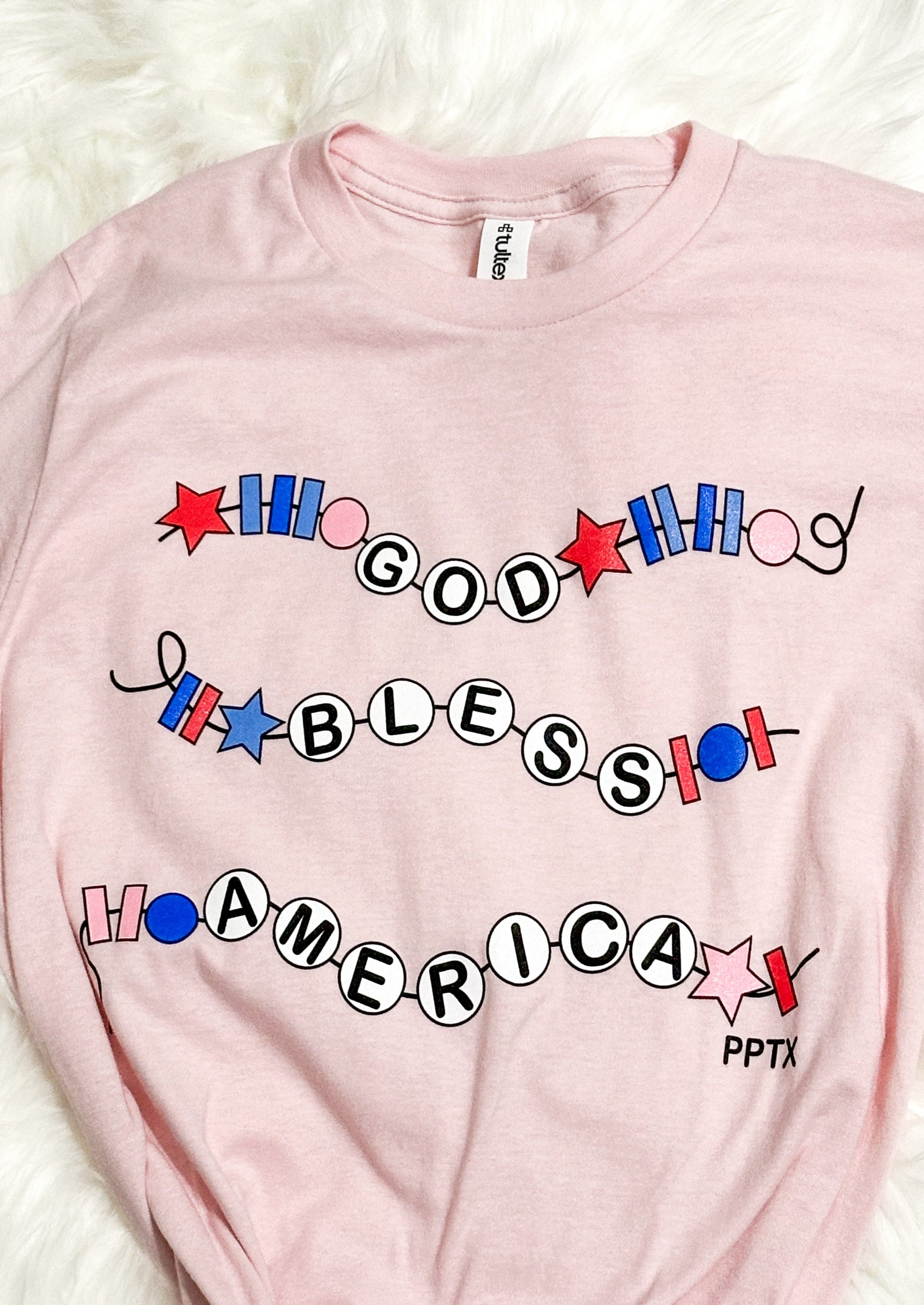 pink tee shirt with god bless america in a friendship bracelet style across the front
