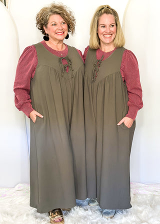 Charcoal gray sleeveless woven jumpsuit with ribbon tie neckline, pockets, and flowy wide-leg fit.