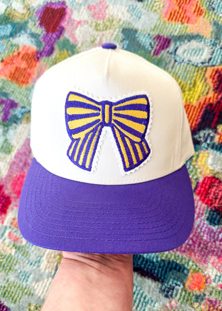 Purple and gold embroidered patch on a retro looking baseball hat.
Snap closure.