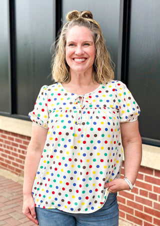 Polka dot print on off white short sleeve top - dots are black, yellow, red, blue and green - tie neck