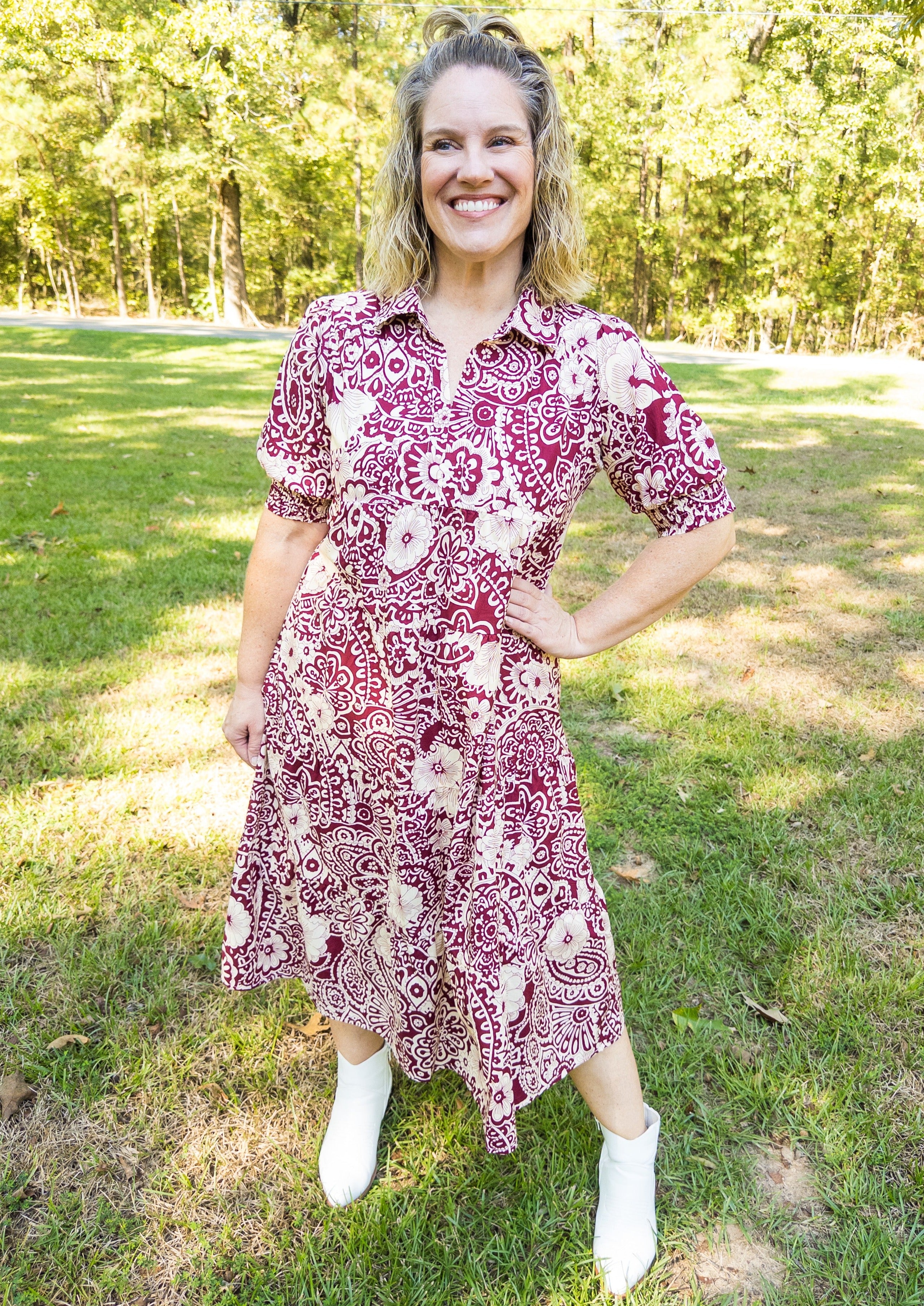 Off white abstract design with flowers on a sangria/wine colored background. Midi length, below the knee. V-neckline with collar. Little balloon sleeve with wide elastic banded cuff above elbow.