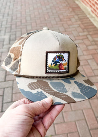 duck stamp embroidery patch on a beige hat with camo bill and camo net back - snapback