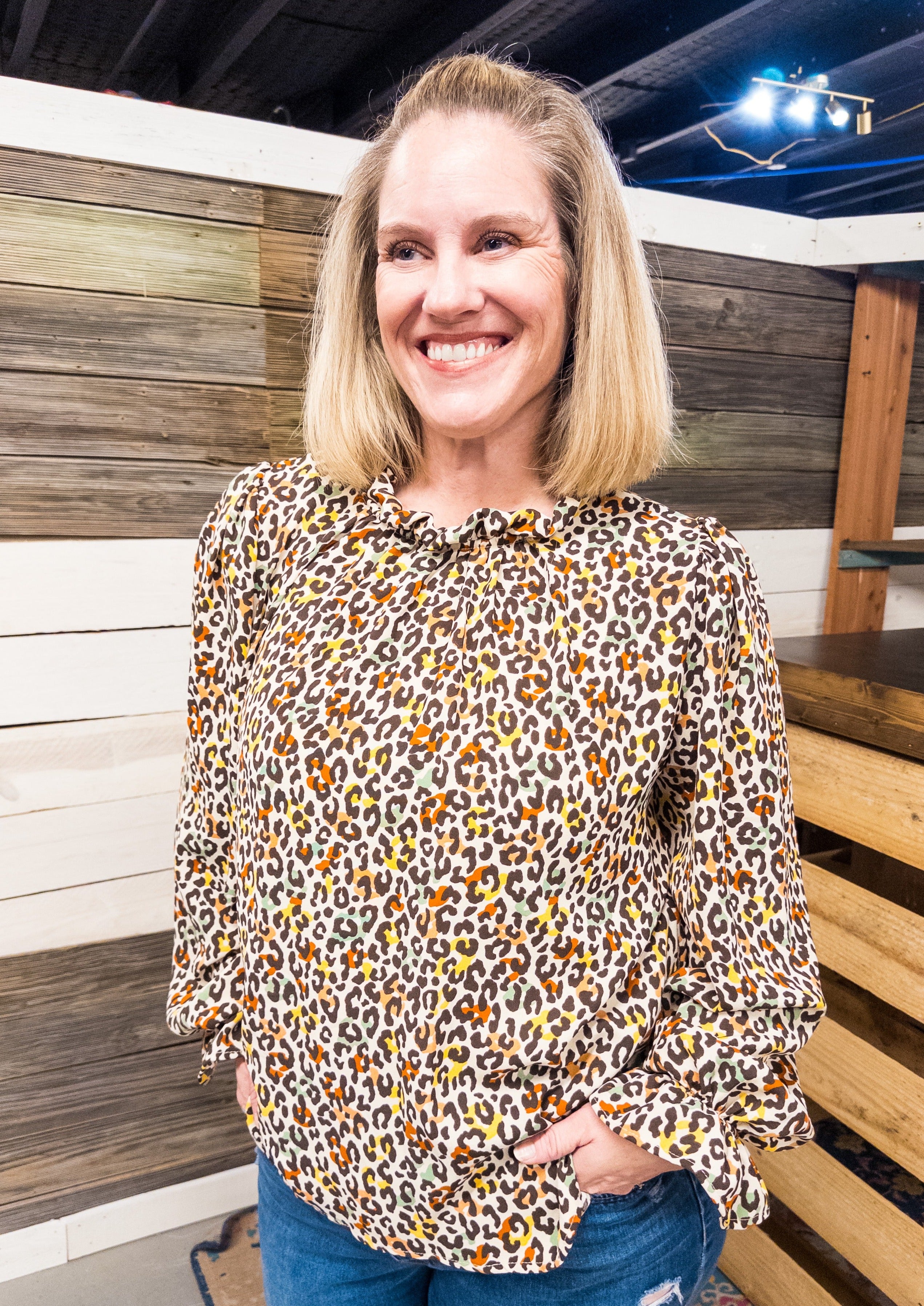 Cream colored long balloon sleeve top with ruffle neck line and ruffle at the cuff. Fall colors are a mix of brown, yellow, orange and tan.