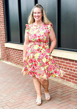 bright floral print smocked waist dress with pockets, ruffle sleeve and neck and one around the bottom  - print colors are yellow, pinks, reds and some green