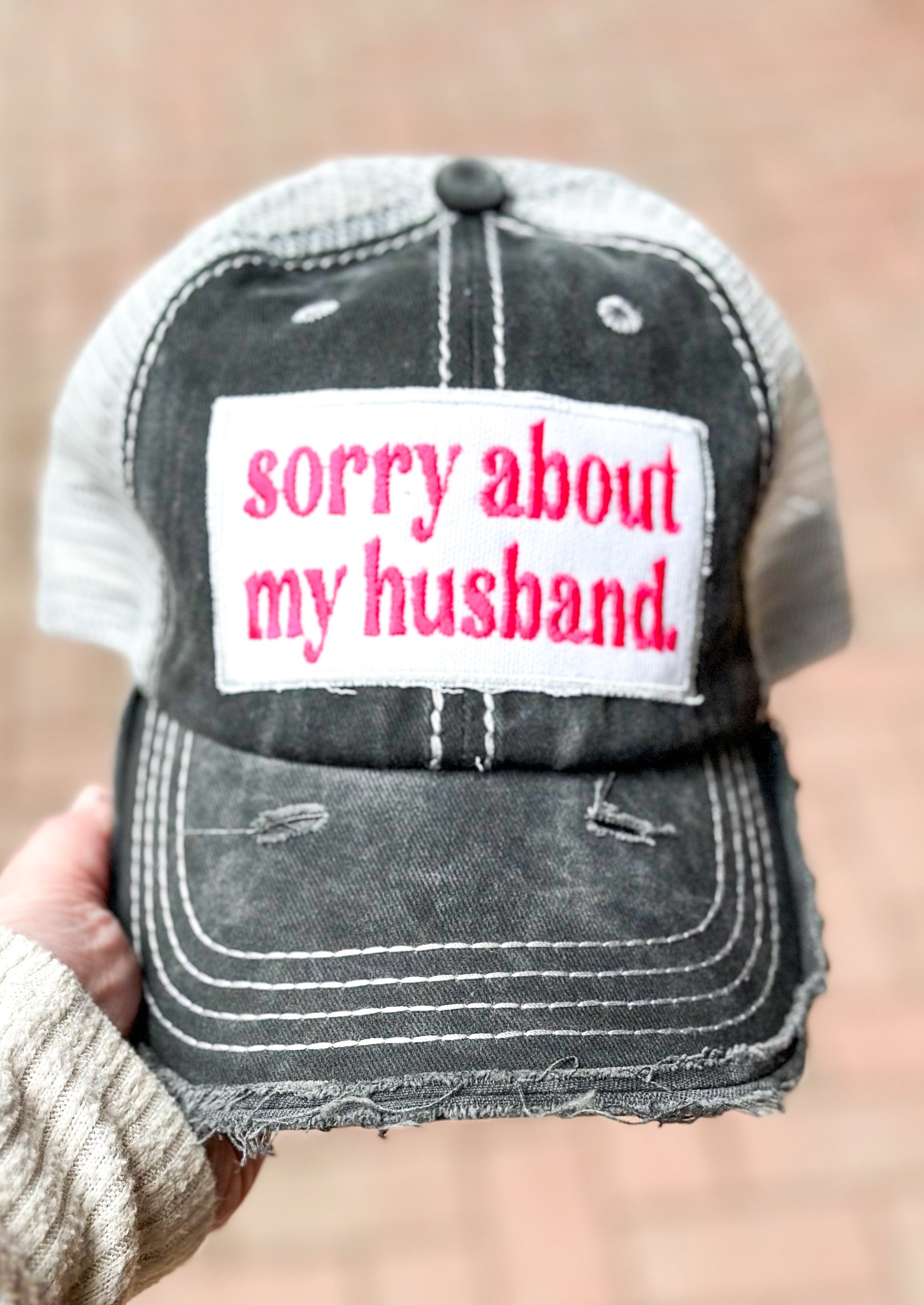 sorry about my husband embroidered patch in hot pink on charcoal gray trucker hat.