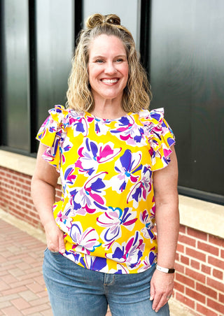 Purple and pink flowers on a yellow top with double ruffle sleeve