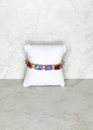 Bracelet with purple gemstones on a white cushion against a light gray background