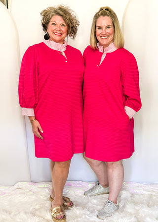 Hot pink quilted dress with striped collar and three-quarter sleeves.