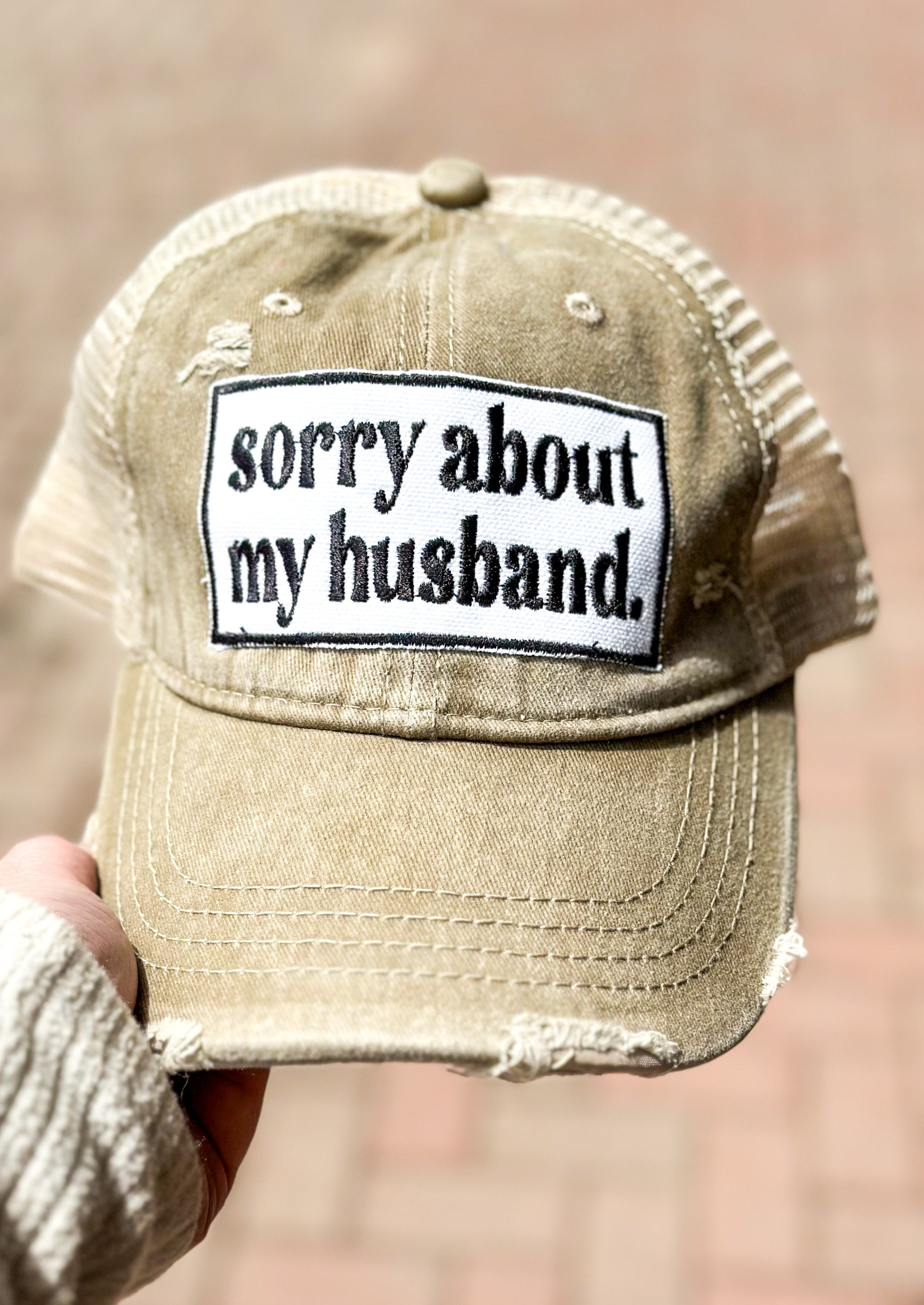 "sorry about my husband" embroidered patch in khaki trucker hat.
