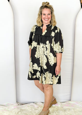 Black knee length dress with large white florals. 3/4 length flowy sleeve. Black scallop detail on chest. Lined