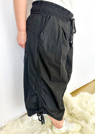 Solid black wide leg crop pants with pockets. Smocked waist with tie closure.  Ribbon cinch detail in the leg.