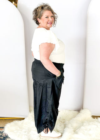Solid black wide leg crop pants with pockets. Smocked waist with tie closure.  Ribbon cinch detail in the leg.