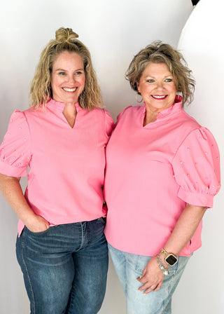 Pink short sleeve top with pearl detail on puff sleeves.  Ruffle collar with notched v-neck