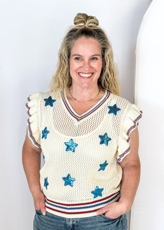 ruffle short sleeve net like cream sweater - need to wear something underneath - blue sequin star patches and red and blue trim around v-neck, bottom banding and ruffle on sleeve