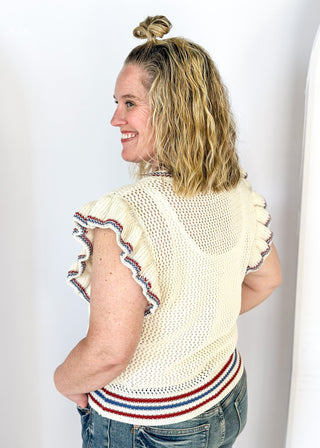 ruffle short sleeve net like cream sweater - need to wear something underneath - blue sequin star patches and red and blue trim around v-neck, bottom banding and ruffle on sleeve