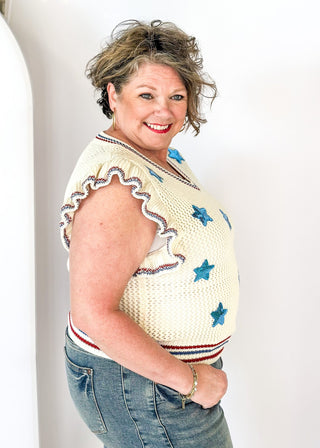ruffle short sleeve net like cream sweater - need to wear something underneath - blue sequin star patches and red and blue trim around v-neck, bottom banding and ruffle on sleeve