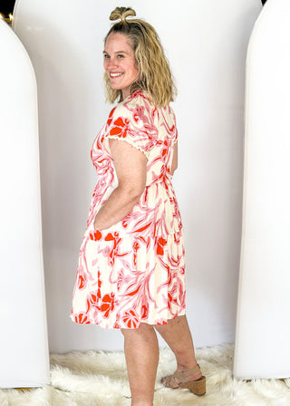 short sleeve dress with v-neck, tiered skirt and elastic waist - ric rack detail around neckline and sleeve - cream background with pink and red floral print - pockets
