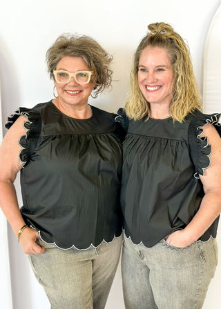black ruffle sleeve top with scalloped trim in white around the sleeve and bottom - round neck - button closure on the back