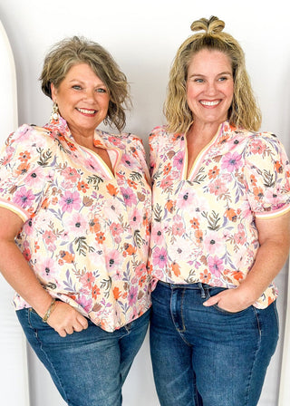 bright floral top with striped detail around arm band and v-neck - purples, peach, blush, pinks and white - short puff sleeve with little shoulder pads