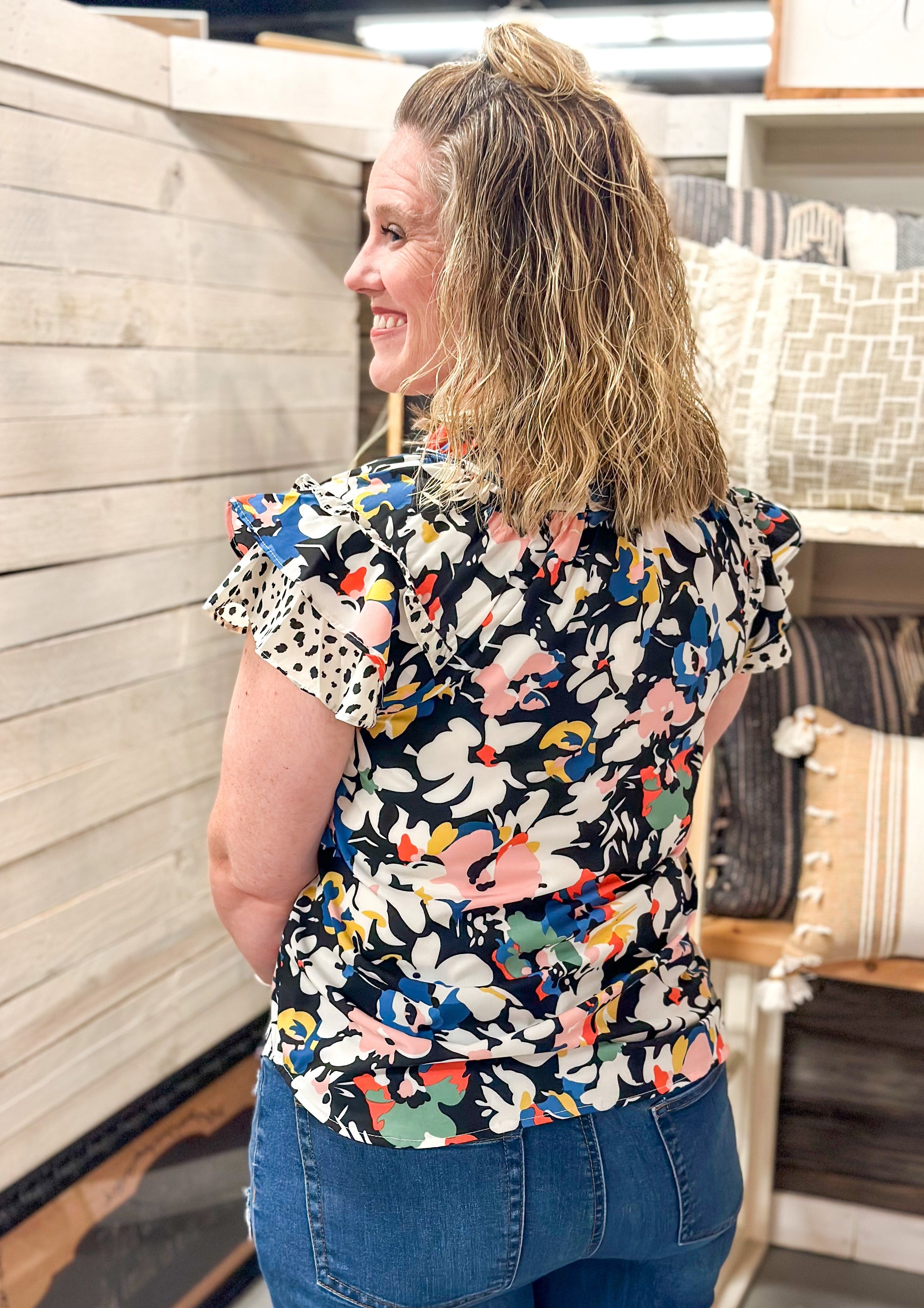 White pink blue yellow red and green flowers over black background. ruffle sleeve and neck with ties