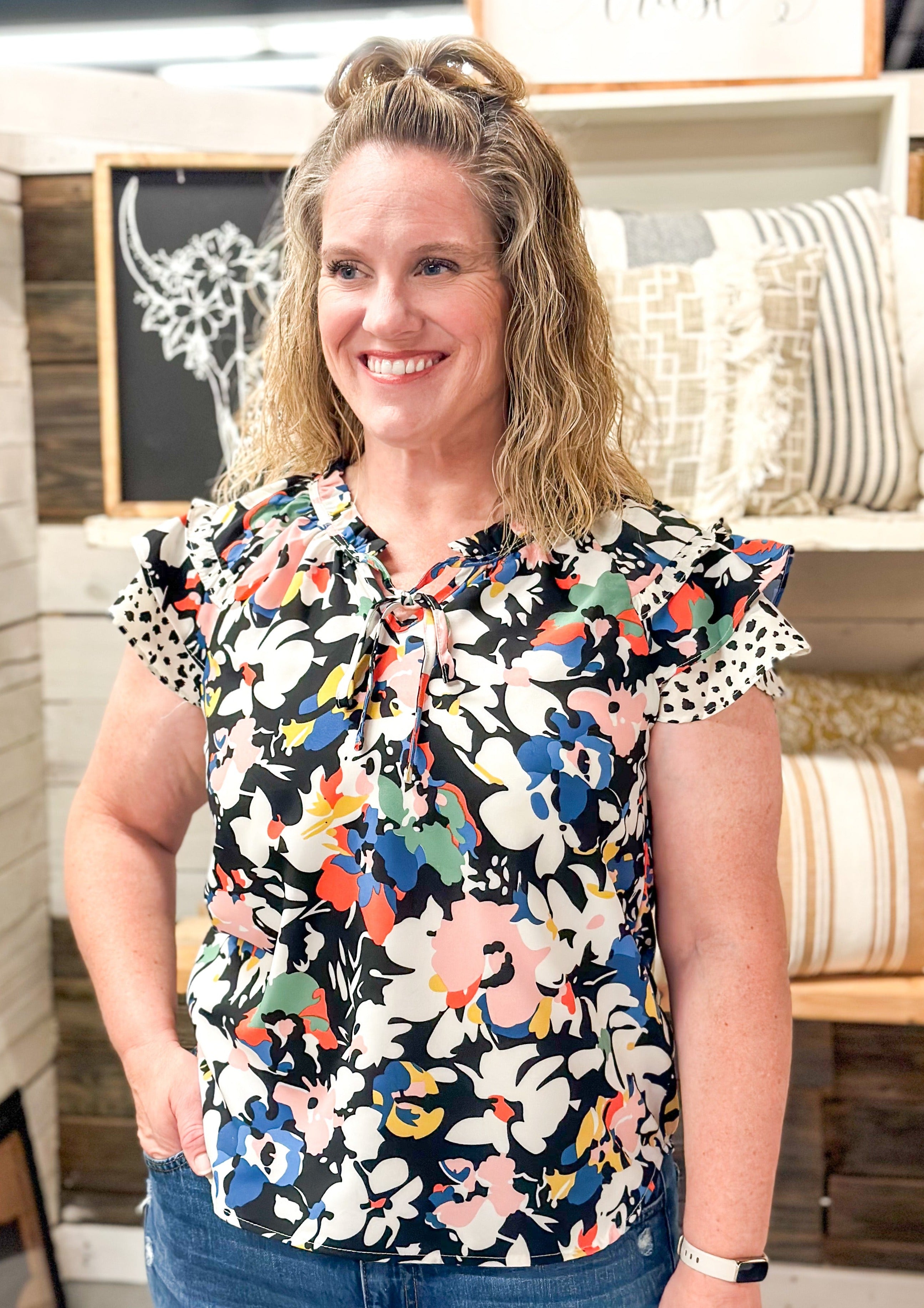 White pink blue yellow red and green flowers over black background. ruffle sleeve and neck with ties