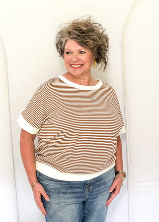 Woman wearing a striped shirt and jeans against a white background