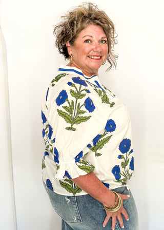 3/4 smocked sleeve white top with large blue blooms. V-neck with blue piping detail. 