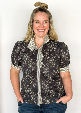 Black with small white florals-short sleeve button up top. Black and white stripe ruffle collar and sleeve binding.  