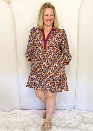 Wine-colored geometric print dress with collared neckline, tiered hem, and 3/4 sleeves.