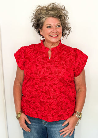 woman wearing red jacquard flutter sleeve blouse with a floral pattern