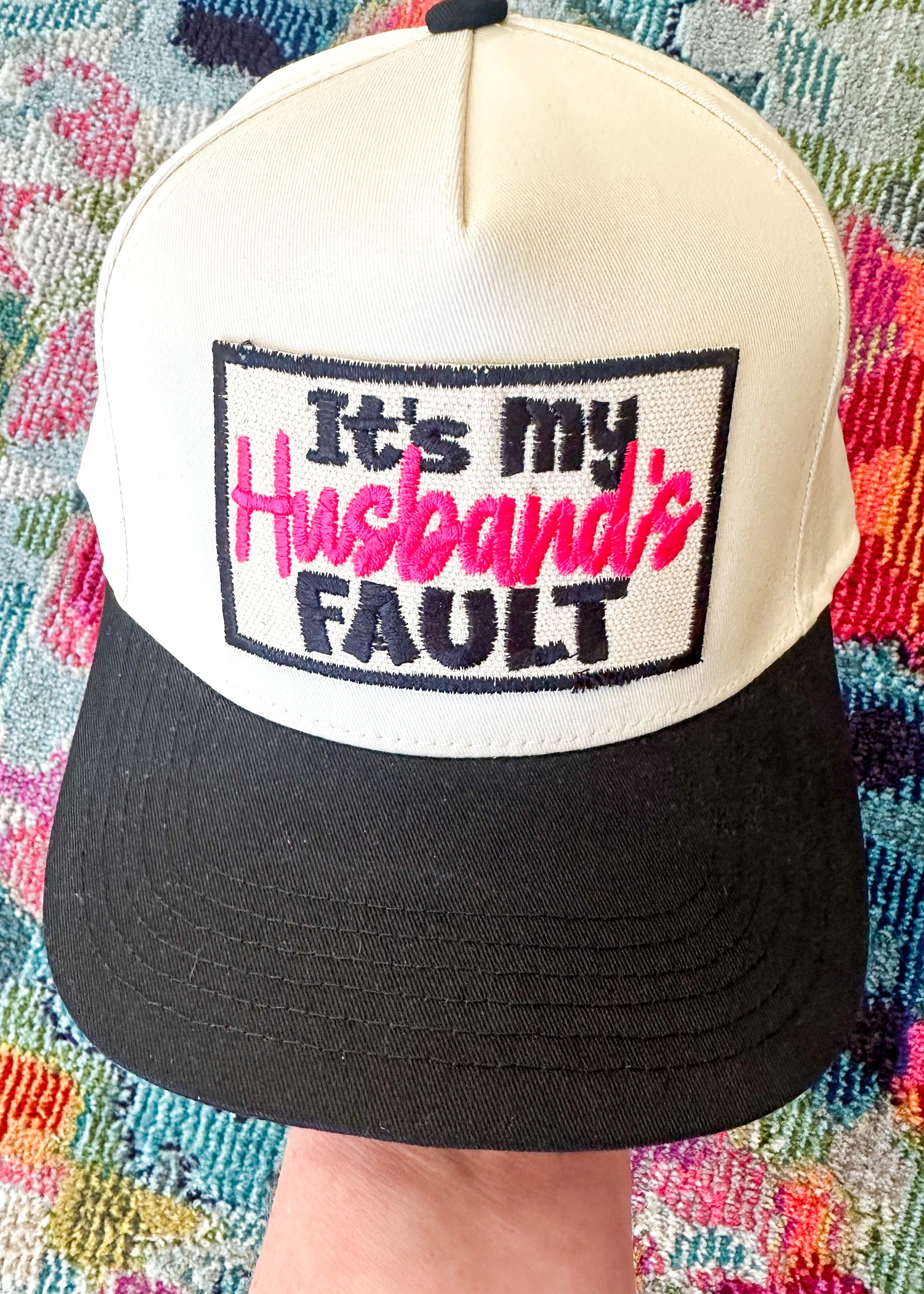 "It's my Husband's FAULT" embroidered patch on a retro style baseball hat.  Black bill cream top

Snap closure.