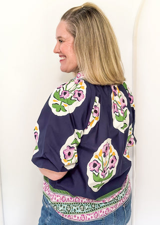 Women’s short sleeve floral blouse in navy with contrast neckline detail, and decorative hem