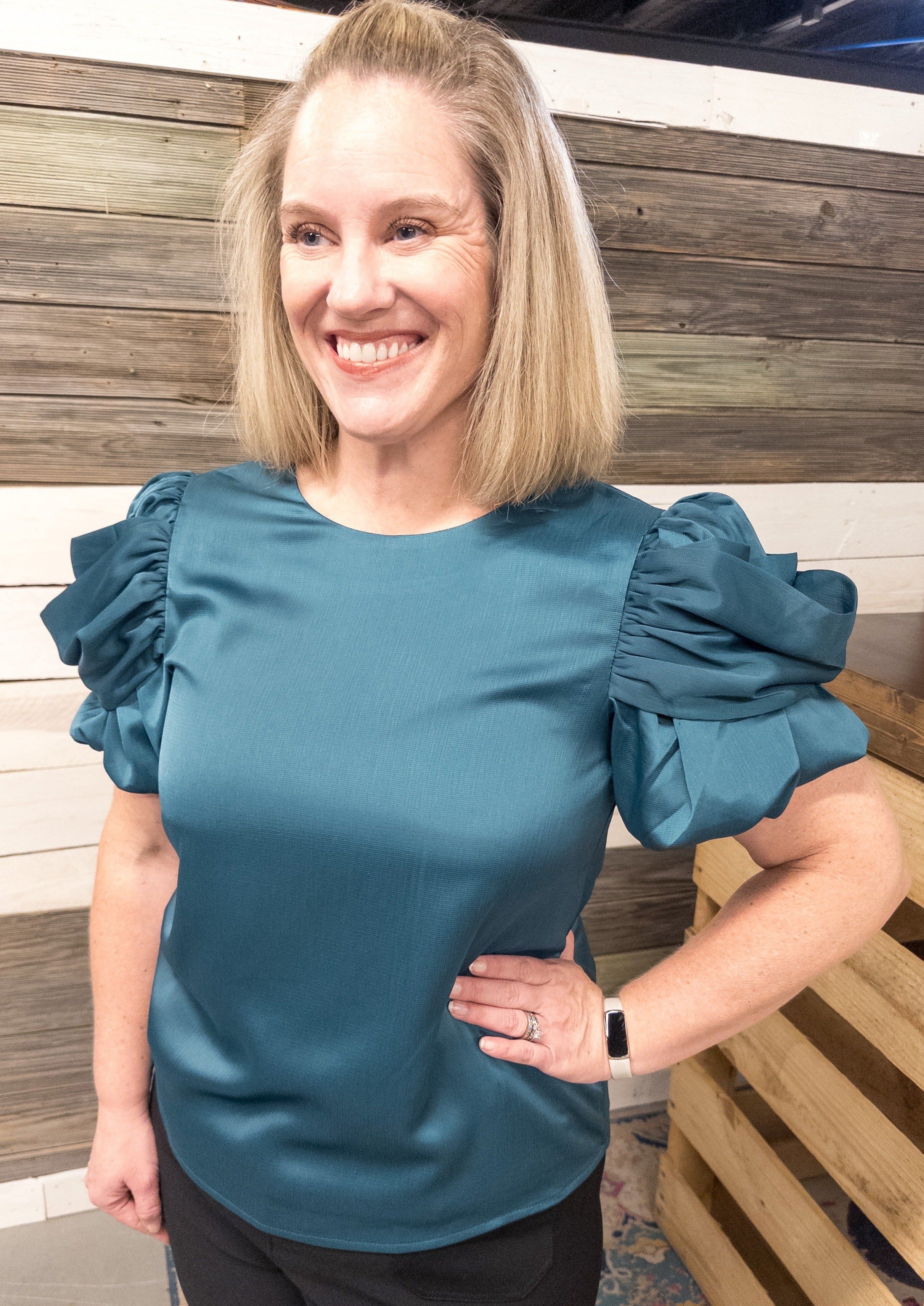 Solid teal colored top with a big and fun draped sleeve detail.