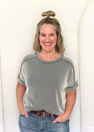 Woman wearing a striped shirt and jeans standing against a white background