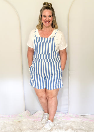 Blue and white striped shorts romper with front pocket and back pockets with heart cut out. 
