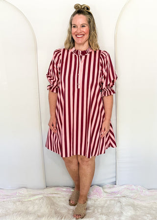 woman wearing pink and wine striped dress with pockets. 