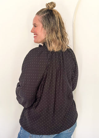 woman in black bubble hem long sleeve top with white dots.