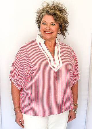 Striped seersucker top in pink and white with short sleeves, relaxed fit, and split neckline.
