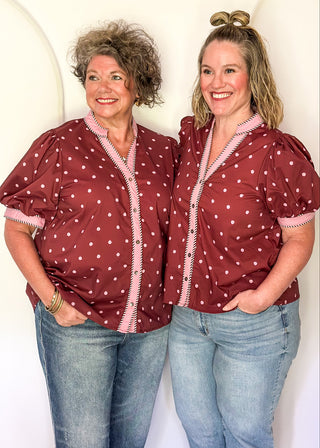 2 women wearing burgundy button up top with polka dots. 