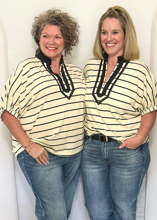 Cream and black striped dolman top with black trim and flowy short sleeves.