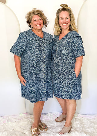 Denim and leopard print jacquard dress with short sleeves and pockets.  Sailor Collar with tie at the v-neck.  Buttons up the front of the dress and hits above the knee. 