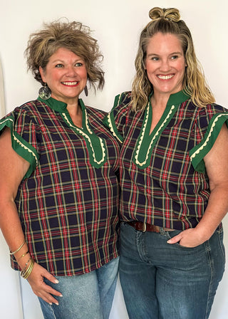 Navy plaid flutter sleeve top with green contrast neckline and scallop trim detail