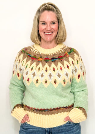 woman modeling a cozy long sleeve sweater with geometric pops of color with a cream and light blue base