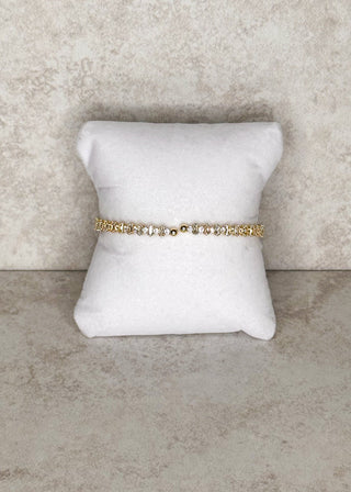 Delicate gemstone open end bangle displayed on a stand