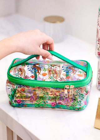 Clear makeup bag with colorful floral design held by a hand on a white surface.