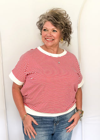 Woman wearing a red and white striped shirt and blue jeans against a white background