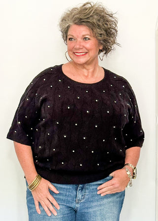 woman wearing black sweater with rhinestones, paired with jeans